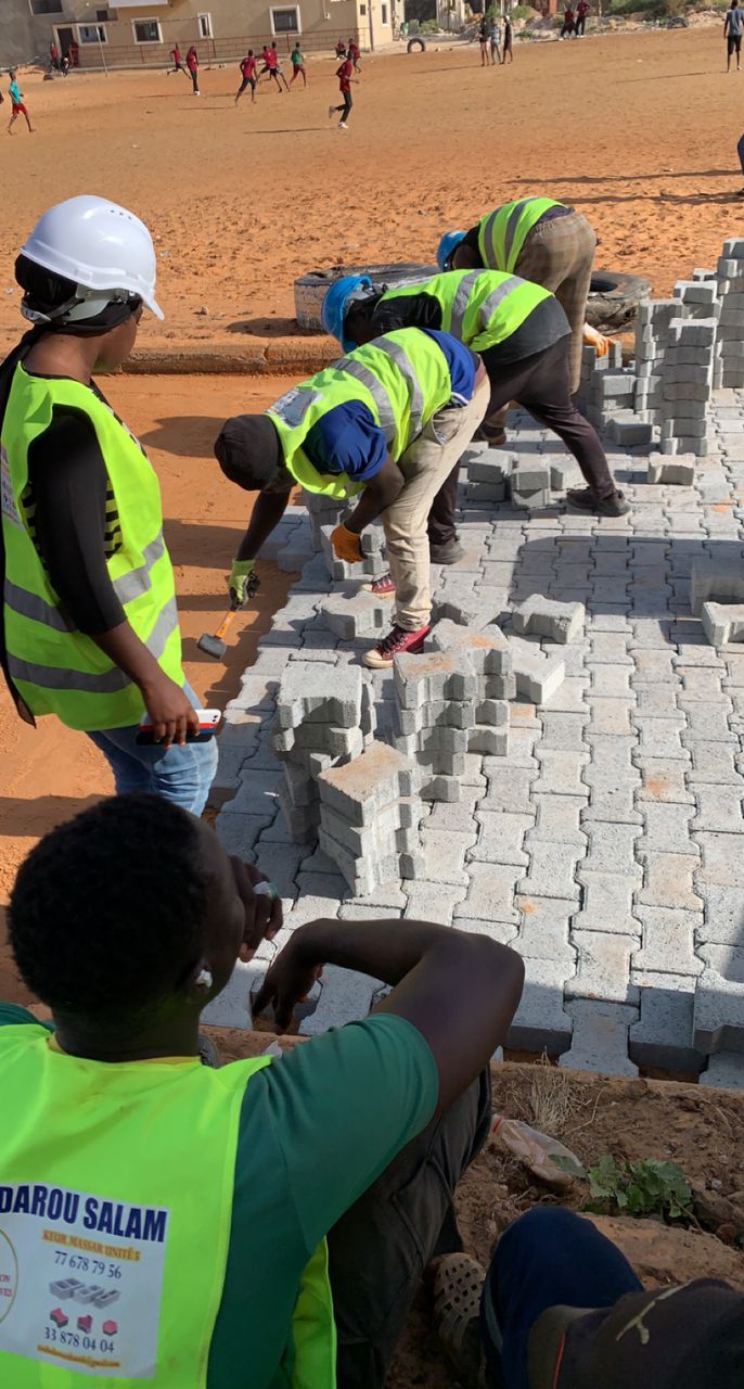 a group of people in vests working on a brick walkway